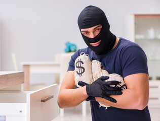 Robber wearing balaclava stealing valuable things
