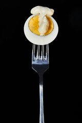 Sliced egg with mayonnaise on a fork