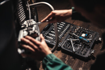 Fototapeta na wymiar A tool box lies on the floor of the garage. A man is repairing a motorcycle.