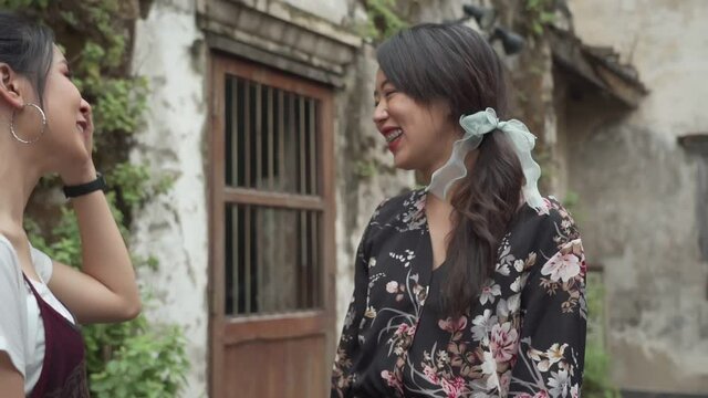 Asian young age female having friendship conversation, outdoor park natural light, new normal life, two girlfriends standing outside old town building slow motion, lesbian couple lgbt pride lover