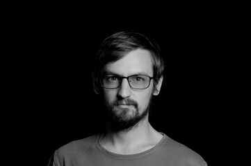 portrait of a guy with a beard in glasses on a black background