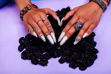woman hands with long nails manicure holding dry fruits in shape of heart on purple background