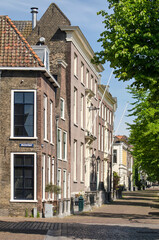 Fototapeta na wymiar Schiedam, The Netherlands, May 18, 2020: traditional brick houses at the junction of Walisstraat and Lange Haven canal in the historic center of the gin capital