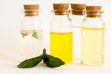 Beautiful photo of small bottles with cork stoppers filled with fantastic fragrant oil, essential oils, peppermint, rose water and daisies