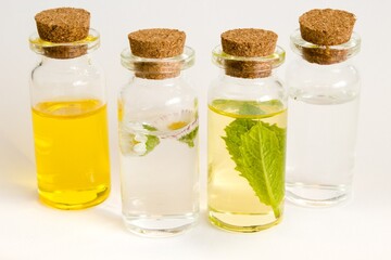 Beautiful photo of small bottles with cork stoppers filled with fantastic fragrant oil, essential oils, peppermint, rose water and daisies