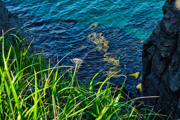top view to the edge of a steep cliff with turquoise sea background on a summer day at sunrise . Nature and outdoor concept.