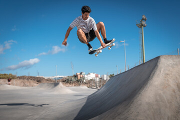 Hombre joven hace un truco llamado "boneless" en rampa con su tabla de skate en un parque.