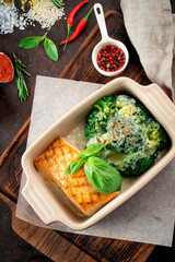 Baked salmon fillet with broccoli on a wooden table with spices, a recipe for a healthy dinner