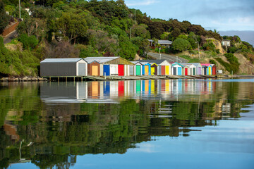 Colorful Boat Sheds with beautiful reflection on daytime  at Duvauchelle, Akaroa Harbour on Banks Peninsula in South Island, New Zealand.