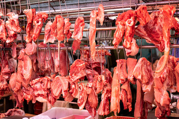A large variety of pork of different parts of a pig hanging in a Chinese local butchery
