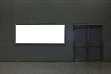 Billboard on a gray wall indoors next to a swing door.