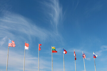 Flags of countries on flagpoles against the blue sky, copy space.