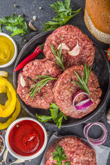 Cooking burger background. Set various cheeseburger  and beefburger ingredients - bun, tomatoes, onion, lettuce, sauces, cheese and raw burger cutlets, ready for barbecue grill. Burger bbq party fest 