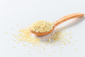 White sesame seeds in a wooden spoon on white background.