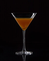 Cocktail glass with orange juice on black background