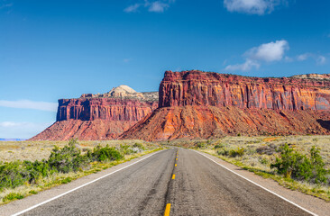 The road running through the dry prairie and rests on the red mountain.