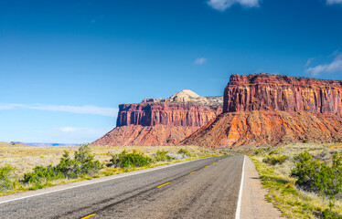 The road running through the dry prairie and rests on the red mountain.