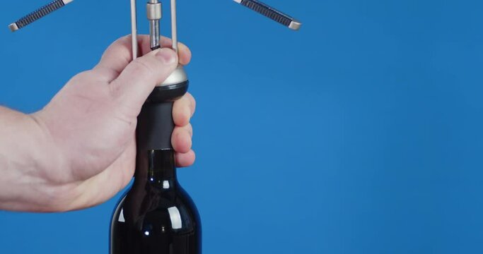 Male hand with a corkscrew open a bottle of wine.