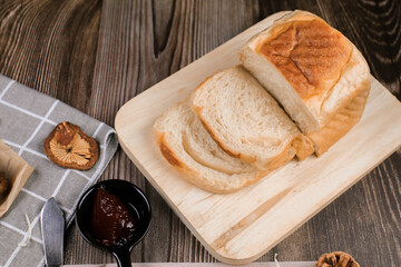 Close up fresh homemade loafs bread and sliced bread on cutting board with jam strawberry on wooden background.Healthy Diet.Prepared from a dough of flour and water, usually by baking.