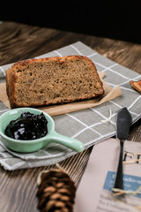 Top view fresh homemade banana bread and sliced bread on cutting board with jam strawberry and blueberry on wooden background.Healthy Diet.Prepared from a dough of flour and water, usually by baking.
