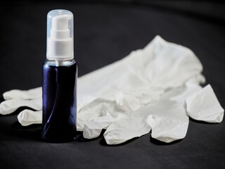 Tube with sanitizer and medical gloves on a black background