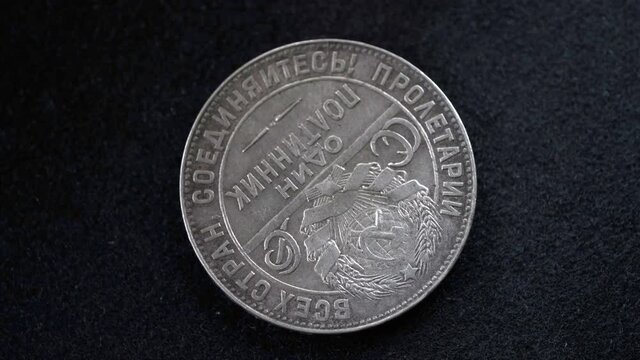 The reverse of a silver Soviet coin of fifty kopecks in denomination of 1924 of release slowly rotates in front of the camera on a black background