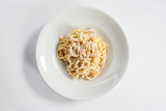 Tonnarelli cacio e pepe is a typical Lazio specialty in Italy spaghetti with pecorino cheese and pepper isolated on white background