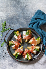Summer snacks. Pear appetizer with jamon, arugula and brie cheese on a light stone table. Top view flat lay background. Copy space.