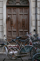 Fototapeta na wymiar vertical photo of bicycles standing on the street against the background of an old wooden arched door
