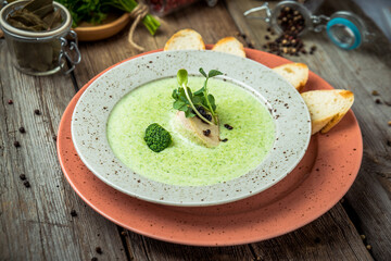 Spinach cream soup in bowl on white rustic table, top view