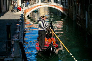 Fototapeta na wymiar horizontal photo from the back of a tall gondolier floating on a gondola along the Venetian canal