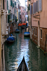 Fototapeta na wymiar vertical photo of a narrow venetian canal flowing between brick buildings