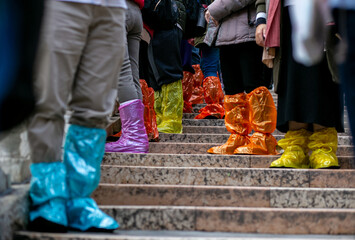 horizontal closeup photo of a group of tourists standing in shoe covers on a stone staircase