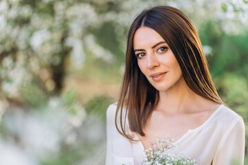 Amazing young woman posing in Blooming tree orchard at spring. Beautiful happy young woman enjoying smell in a flowering spring garden