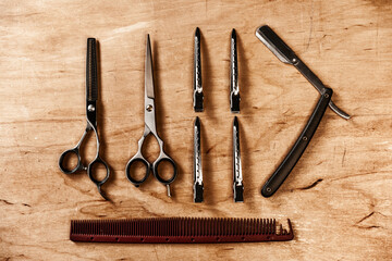 The hairdressing tool lies on a wooden table. Hairdressing comb, scissors and razor.