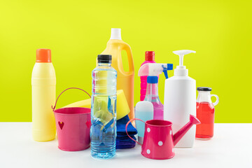 Plastic bottles of cleaning products set on white table.