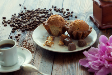 Coffee grinder and cup of coffee on brown wooden background with cakes. Breakfast concept