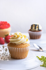cupcake de vainilla servidos en un plato con fresas en el fondo