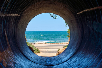 View of the sea through a tunnel with clear blue sky, tunnel vision on the ocean