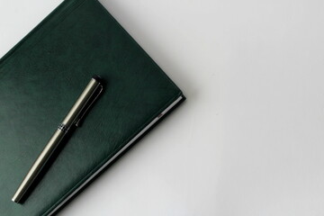 green notebook with pen on a white background