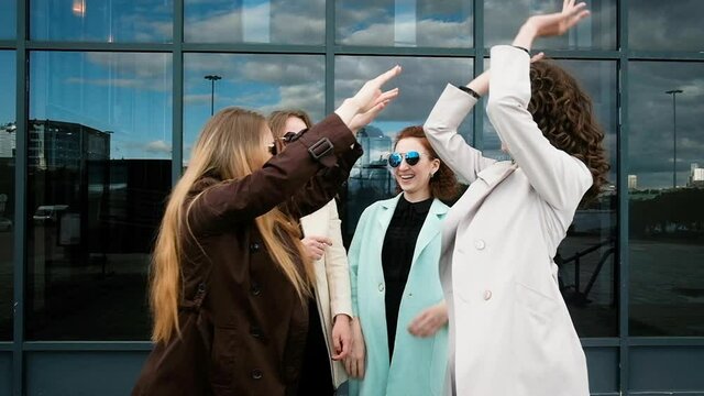 young women give five to each other. girls having fun, fooling around in the city. teamwork concept Walk in the fresh air. Five girls 20-25 years old
