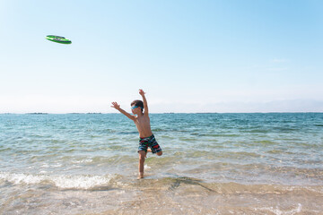 Young boy playing with a frisbee disc on the beach