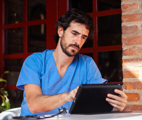 Male nurse working with his tablet outside.