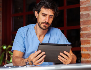 Male nurse working with his tablet outside.