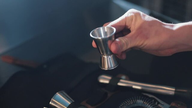 Tools for making cocktails. special bag for cocktails tools. Kitchen Appliance. the bartender takes a measuring cup in his hands