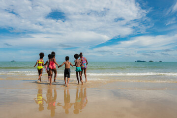 Group of African American children run on beach to the sea 