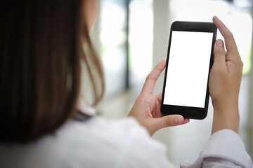 Cropped shot view of woman hands holding smart phone with blank copy space screen for your text message or information content, female reading text message on cell telephone during in urban setting.