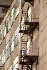 Fototapeta premium Close up of a rusty staircase on a building with large windows