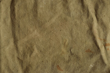 Old, crumpled and dirty khaki color tarpaulin, detailed texture. Fabric of a vintage army military...