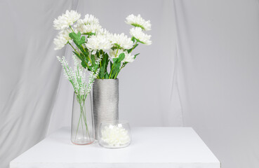 A group of white plastic flowers on the table with the background of white